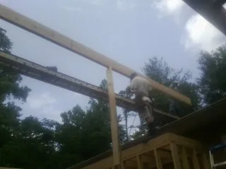 Carpenter setting a ridge beam over a new addition frame — Ice Dam Removal by Roofing Brothers in Welcome