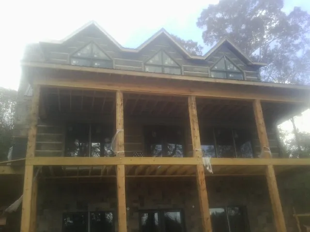 Dormers and porch framing on a large log home under construction — Roof Coating work by our crew in Welcome