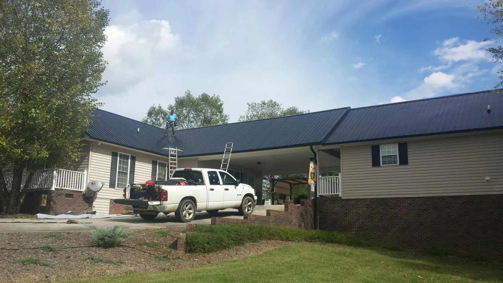 Black metal roof over a home and attached breezeway with ladders set in Welcome