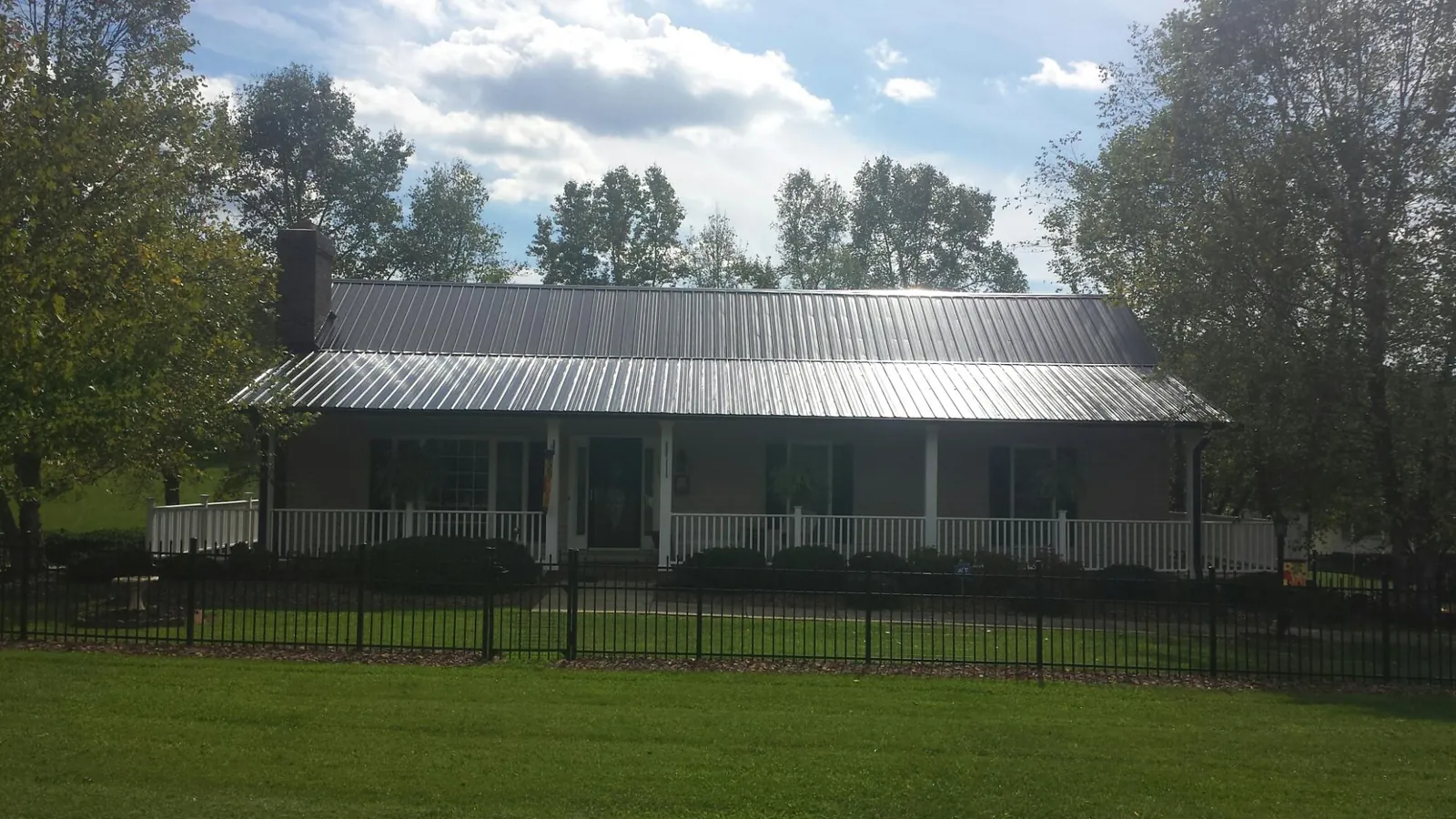 Gray metal roof on a brick ranch with a full width front porch — Gutter Guard Installation work by our crew in Welcome