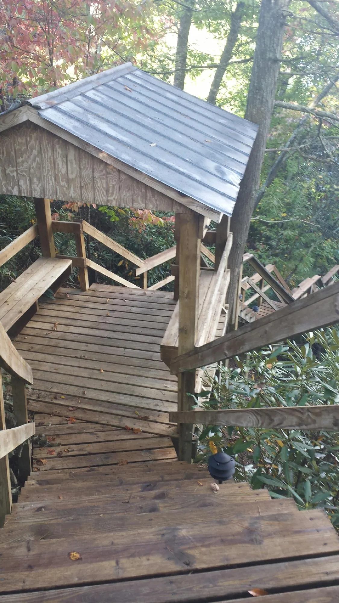 Metal roofed shelter over wooden steps on a wooded walkway — Skylight Repair & Installation work by our crew in Welcome