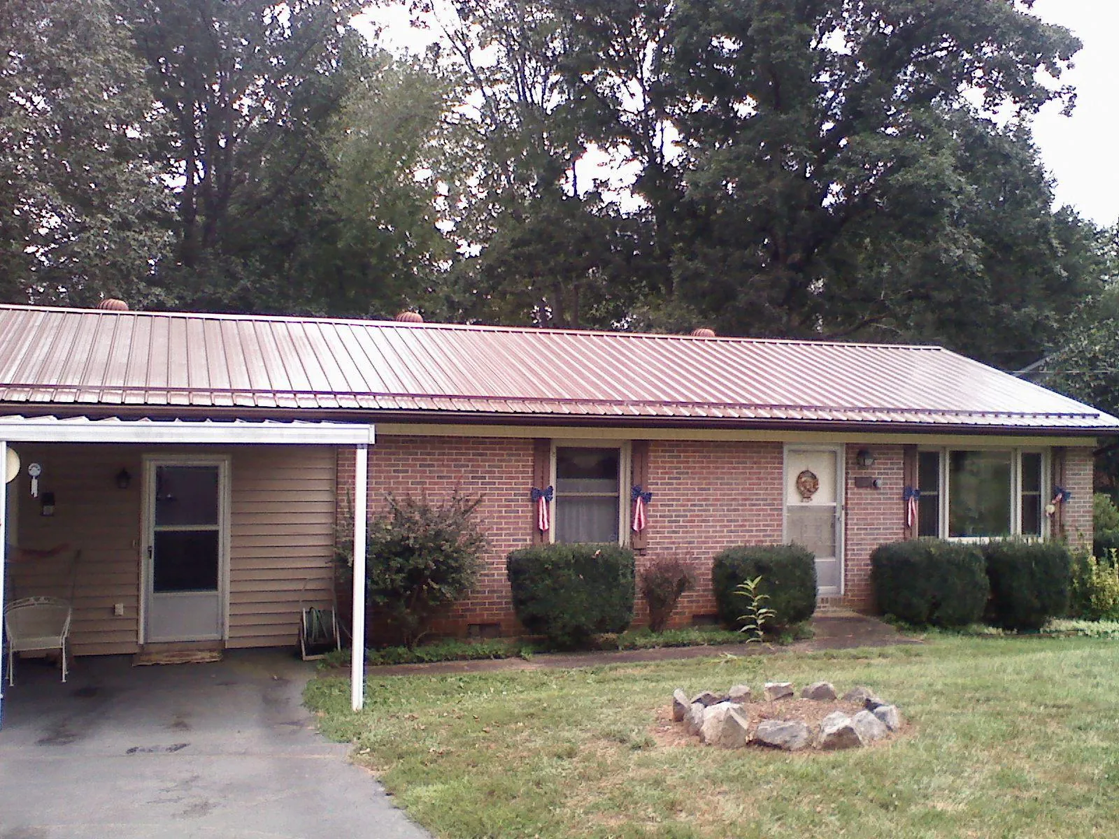 Bronze metal roof and carport on a brick ranch home — Roof Repair work by our crew in Welcome