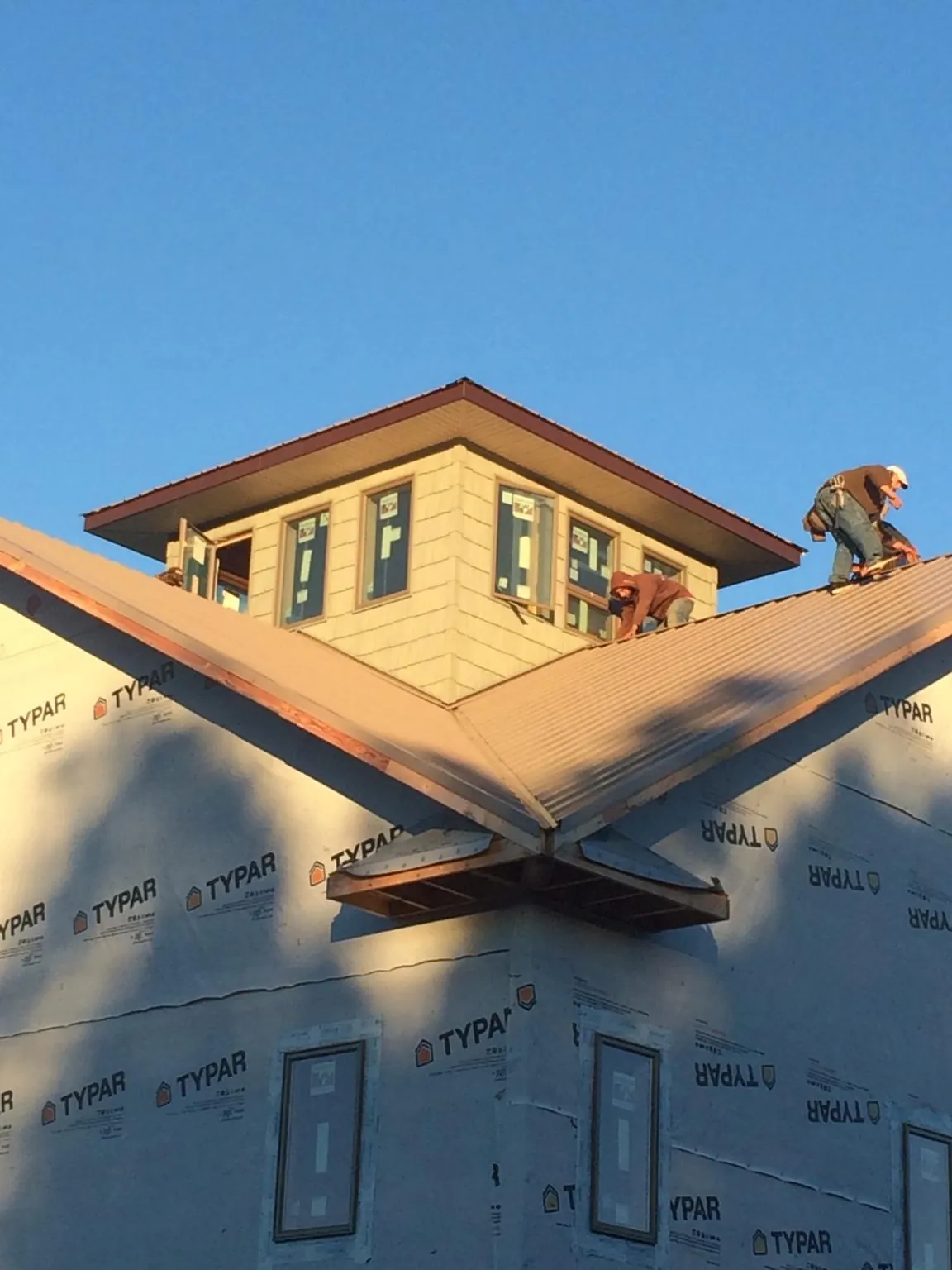 Roofers working around a rooftop cupola on a new metal roof at sunset — Roof Waterproofing in Welcome by Roofing Brothers
